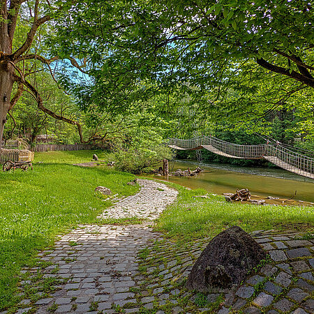 Die Hängebrücke im Mühlendorf liegt idyllisch im Grünen.