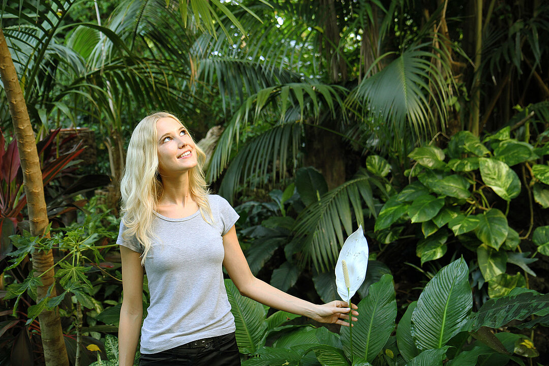 Eine junge Frau schaut sich neugierig in der Dschungelwelt um.