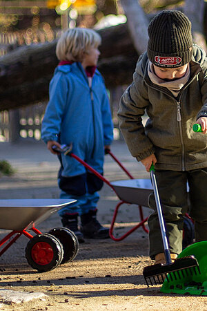 Ein Kind mit einer grünen Schaufel sammelt Tierkot ein.