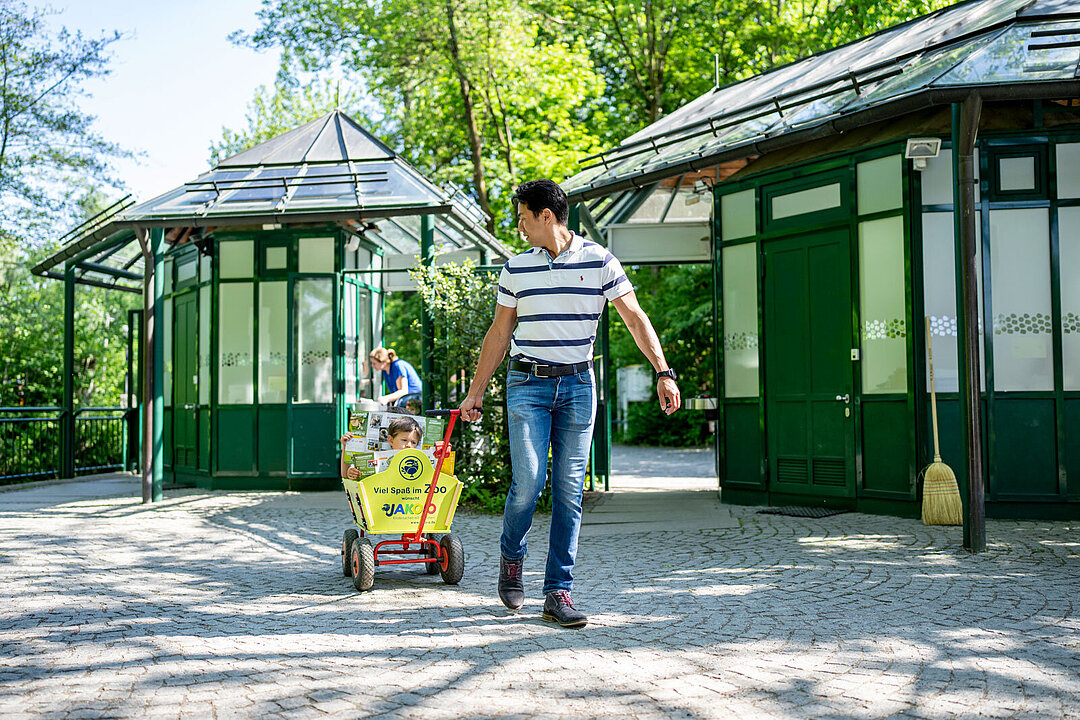 Zwei Kinder sitzen im Bollerwagen und werden von ihrem Vater gezogen.