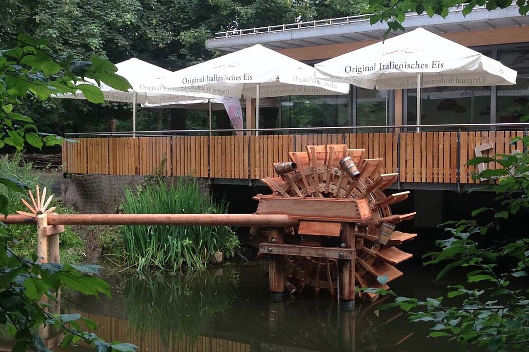 Blick auf das Café Mühle hinter dem kleinen Bach im Tierpark Hellabrunn.