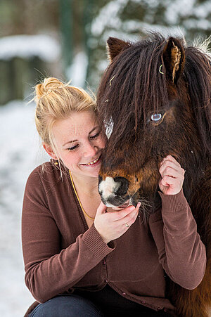 A visitor strokes a Shetland pony.