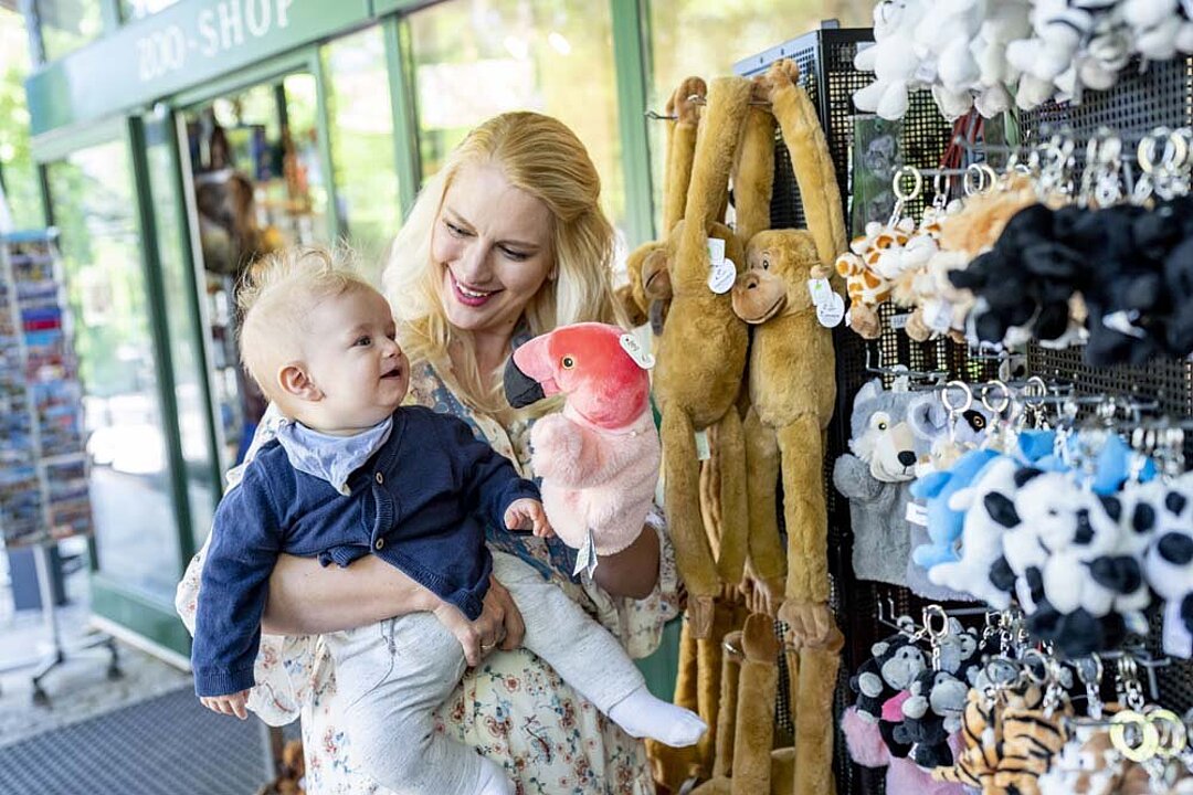 Eine Frau und ihr Baby betrachten das Kaufangebot des Zooshops im Tierpark Hellabrunn.