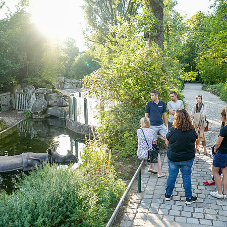 Hellabrunn Führung vor Nashornanlage Ein Zoo-Guide führt eine Gruppe von Besuchern durch den Tierpark.