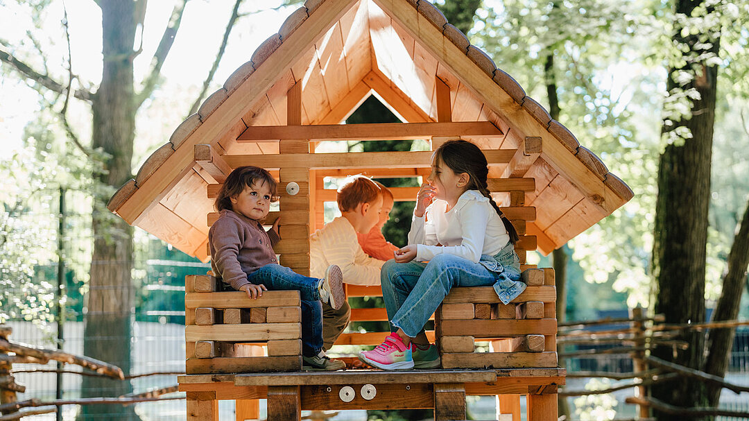 Mehrere Kinder sitzen in einem Kinderspielhaus.