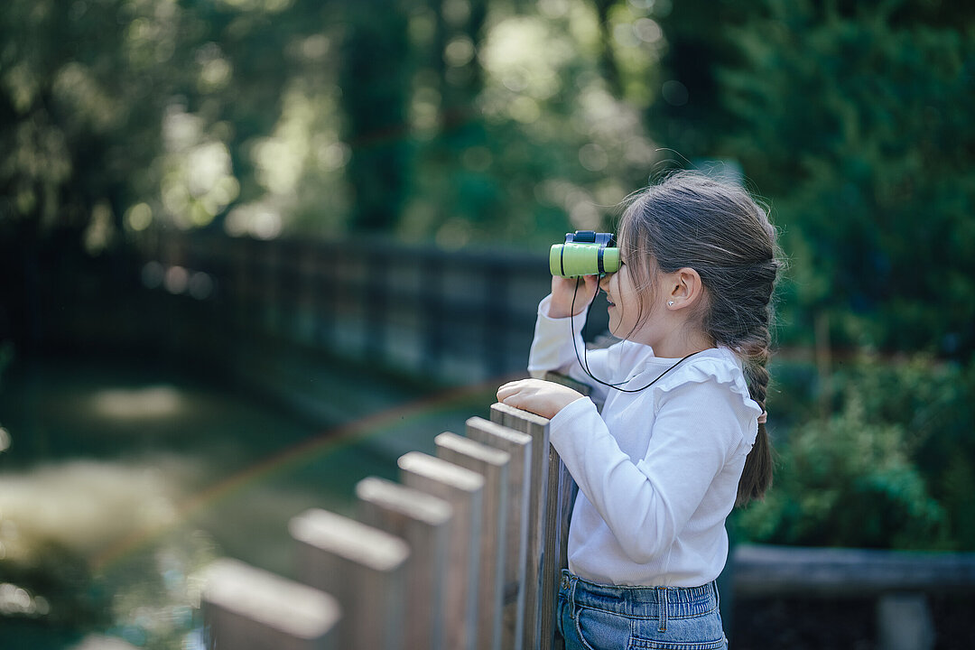 Mädchen mit Fernglas im Tierpark 