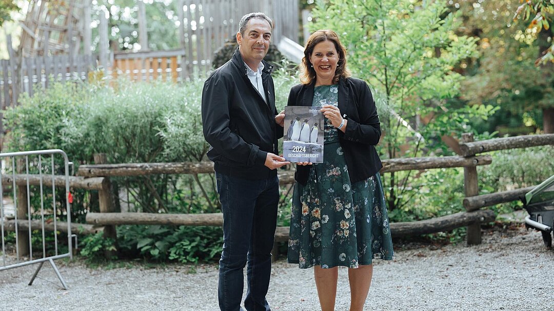 Frau Dietl und Herr Baban halten den Geschäftsbericht 2024 in den Händen.